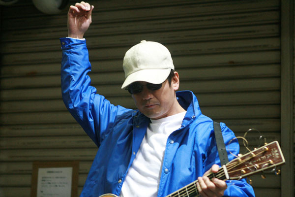 Kenji jouant de la guitare pour gagner sa vie