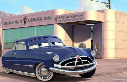 Doc Hudson (Pixar – Cars) Hudson Hornet devant son garage